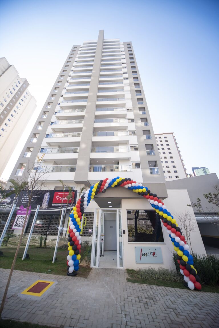 Fachada do Empreendimento residencial Miró Parque com jardim na frente e um muro de vidro, balões coloridos para enfeitar o prédio no dia da sua inauguração